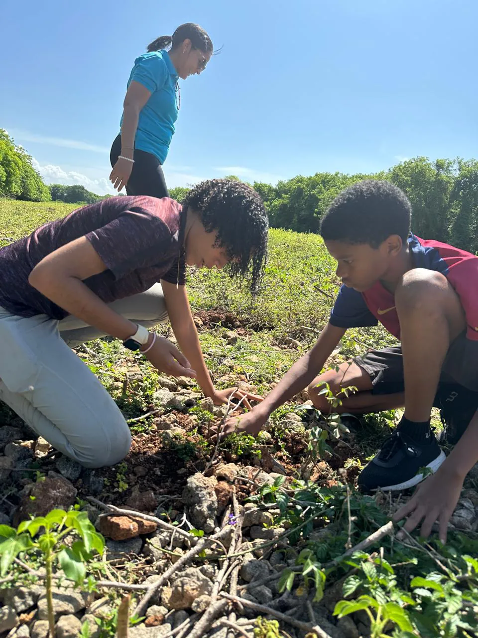 Dos jóvenes de Interact plantan árboles junto a una socia rotaria